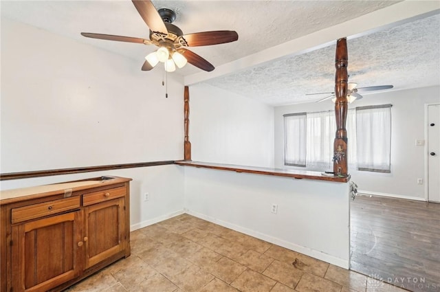 empty room with ceiling fan, baseboards, and a textured ceiling