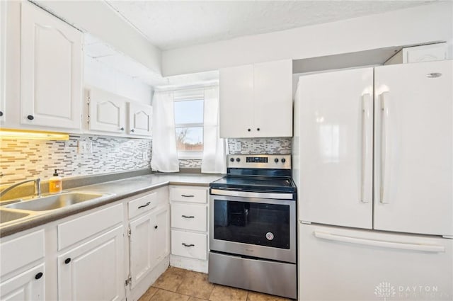 kitchen featuring a sink, white cabinets, freestanding refrigerator, decorative backsplash, and stainless steel electric range oven