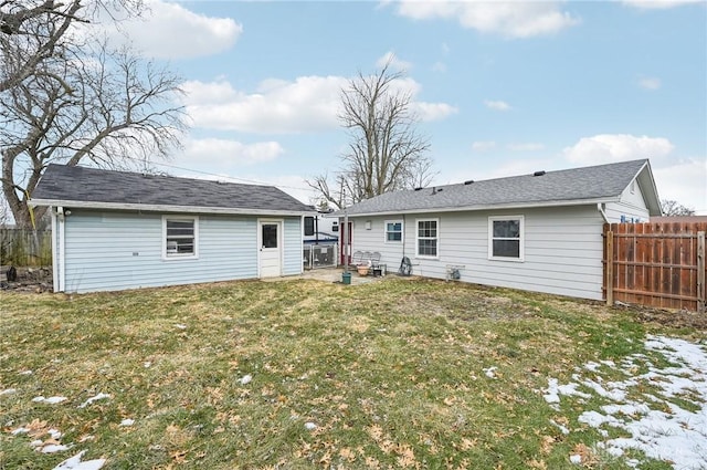 rear view of house featuring fence and a yard