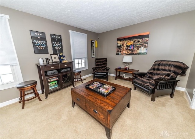 living area with light carpet, a textured ceiling, and baseboards