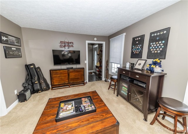 living area with light carpet, baseboards, and a textured ceiling