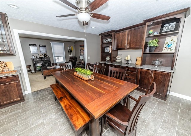 dining space featuring ceiling fan, a textured ceiling, and baseboards