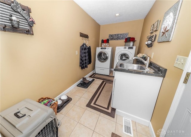 laundry room featuring laundry area, light tile patterned floors, baseboards, washing machine and clothes dryer, and a sink