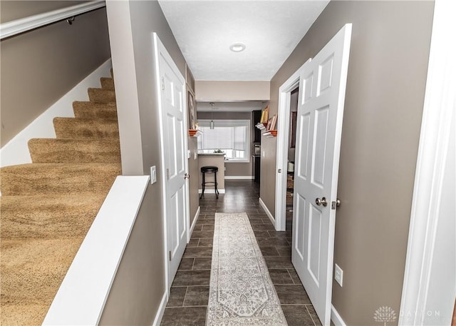 corridor with wood finish floors, stairway, and baseboards