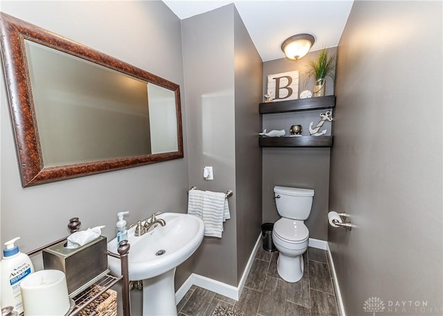 bathroom featuring baseboards, a sink, and toilet