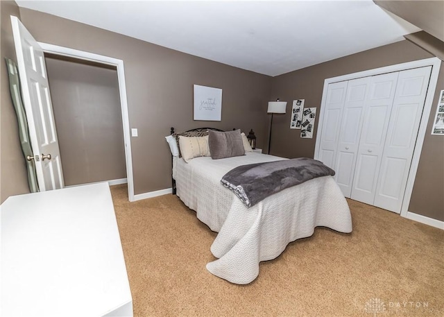 bedroom with a closet, light carpet, and baseboards