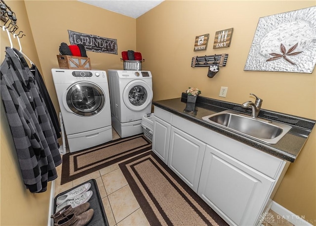 laundry area featuring washer and clothes dryer, light tile patterned flooring, a sink, and cabinet space