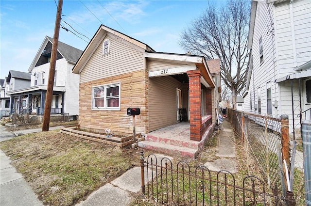 view of side of home featuring stone siding and fence