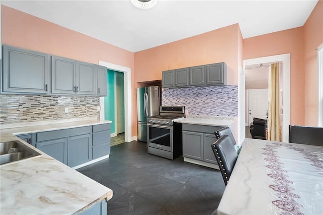 kitchen featuring a sink, stainless steel appliances, tasteful backsplash, and light countertops