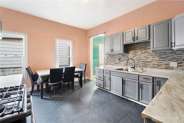 kitchen featuring tasteful backsplash, gray cabinets, and a sink