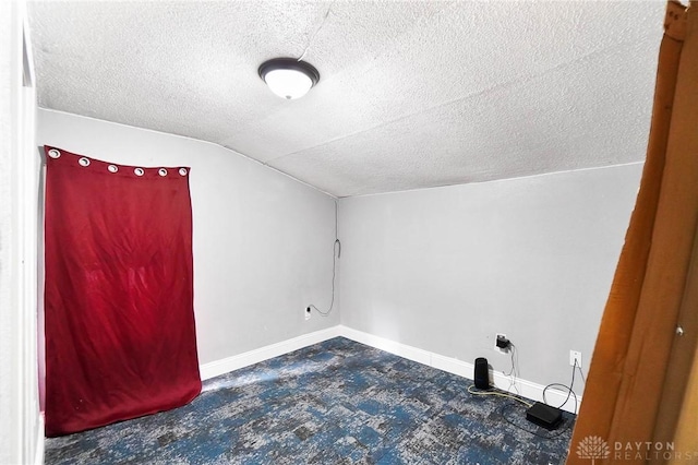 additional living space with lofted ceiling, baseboards, and a textured ceiling