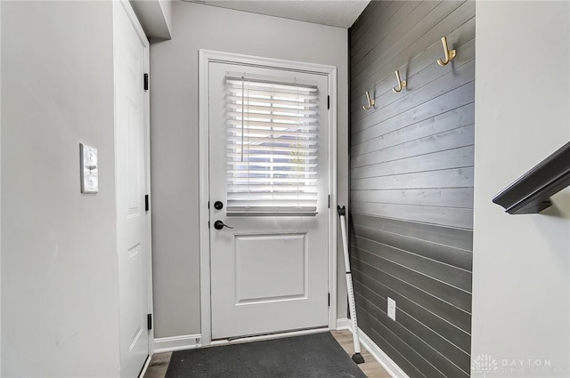 entryway with wood walls, wood finished floors, and baseboards