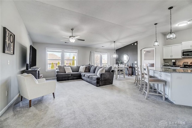 living area featuring ceiling fan, light carpet, arched walkways, and baseboards