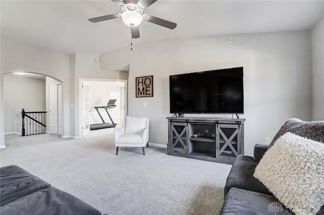 carpeted living area featuring arched walkways, ceiling fan, and baseboards