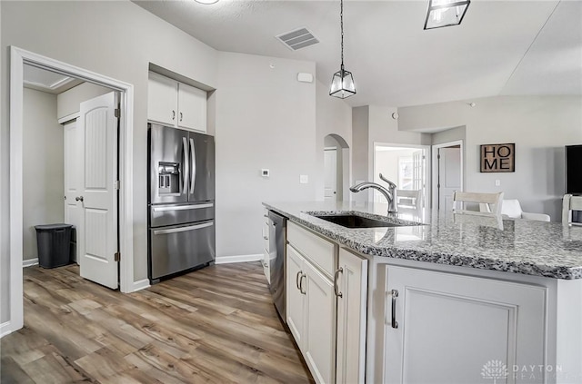 kitchen featuring arched walkways, stainless steel appliances, visible vents, white cabinetry, and a sink