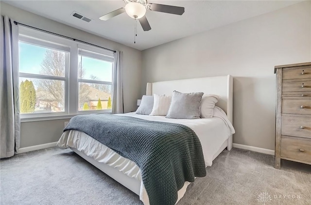 bedroom with light carpet, ceiling fan, visible vents, and baseboards