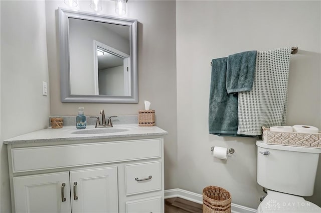 bathroom featuring toilet, baseboards, and vanity