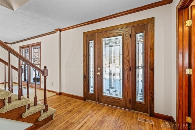 entryway with light wood-style floors, visible vents, baseboards, and stairs