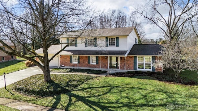 traditional-style house featuring a front yard, concrete driveway, brick siding, and an attached garage