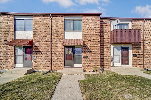 multi unit property featuring a front yard and brick siding