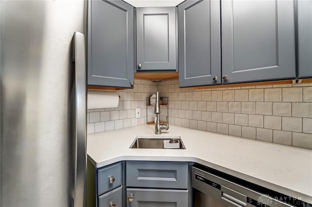 kitchen with light countertops, backsplash, freestanding refrigerator, a sink, and dishwasher