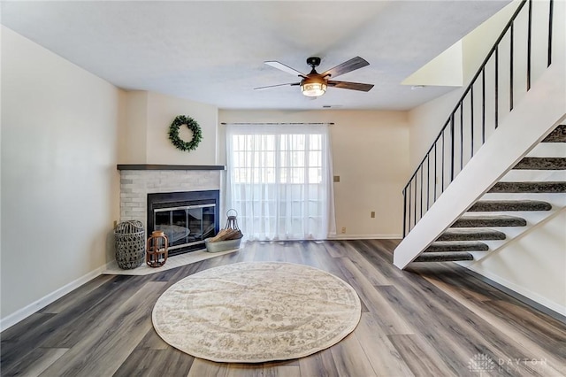 living area with dark wood-type flooring, a fireplace, stairway, and baseboards