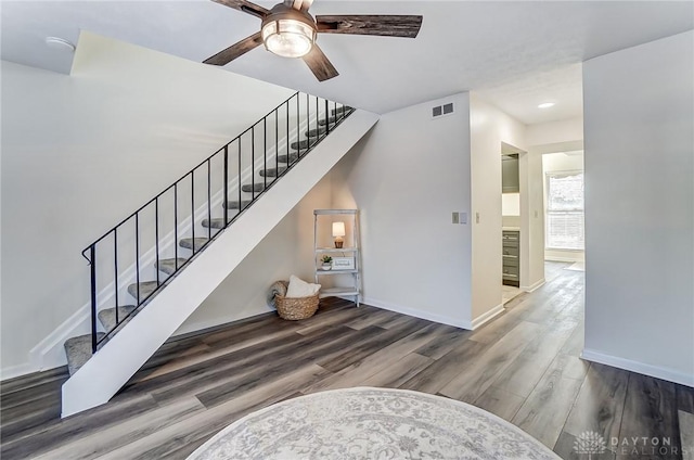 stairs featuring a ceiling fan, wood finished floors, visible vents, and baseboards