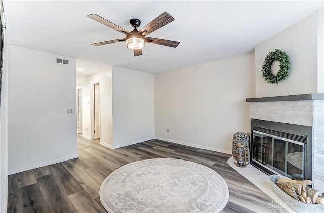 living room with ceiling fan, dark wood-style flooring, a fireplace, visible vents, and baseboards