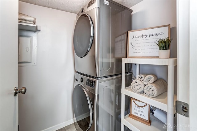 laundry room featuring stacked washer and dryer, baseboards, laundry area, and a textured ceiling