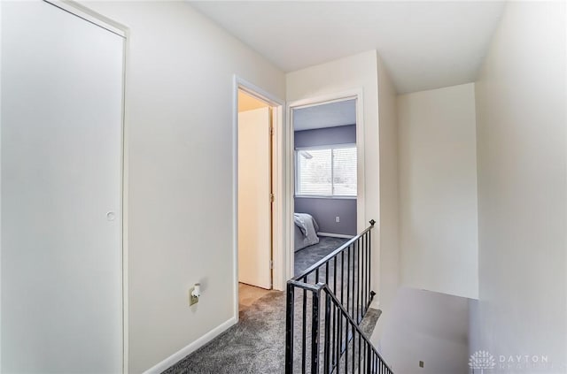 corridor with baseboards and dark carpet