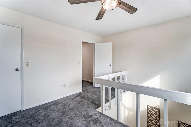 empty room featuring dark carpet, a ceiling fan, and baseboards