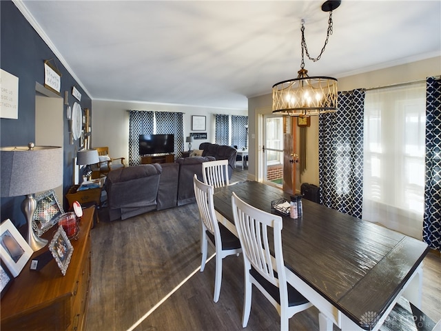 dining space with crown molding, an inviting chandelier, and wood finished floors