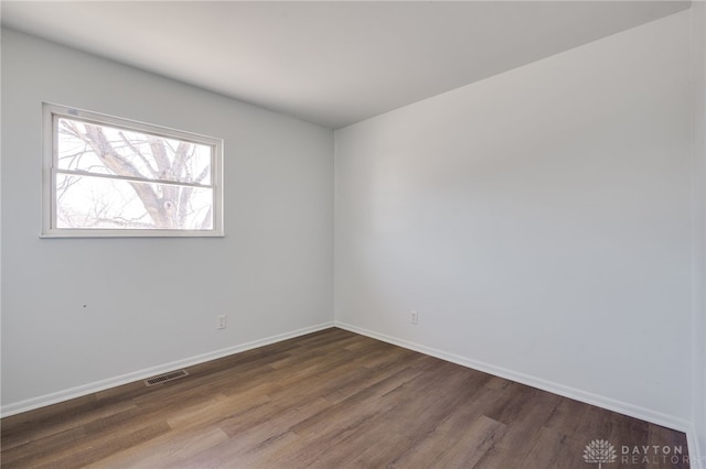 unfurnished room with wood finished floors, visible vents, and baseboards