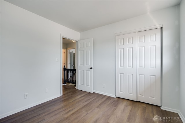 unfurnished bedroom with light wood-type flooring, baseboards, and a closet