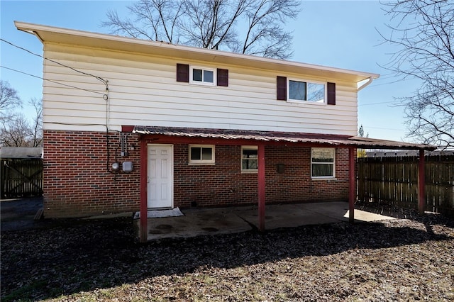 rear view of property with brick siding, a patio area, and fence