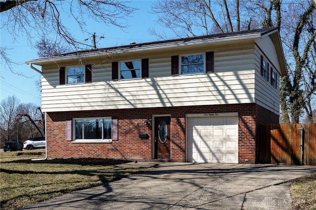 colonial house featuring brick siding, an attached garage, fence, and aphalt driveway