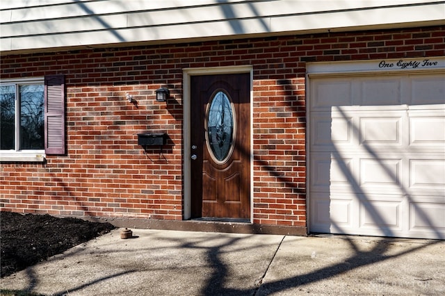 entrance to property with a garage and brick siding