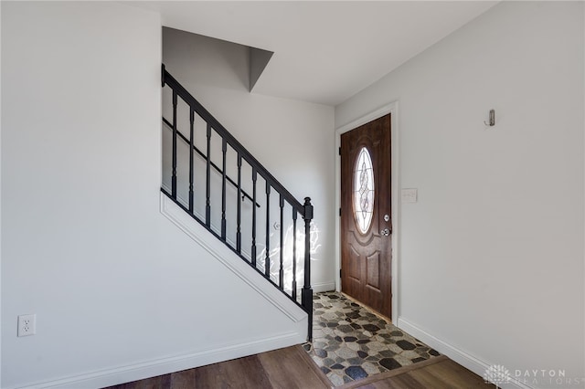 foyer featuring baseboards, stairway, and wood finished floors