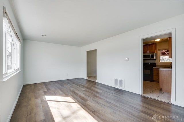 spare room featuring light wood-type flooring, visible vents, and baseboards