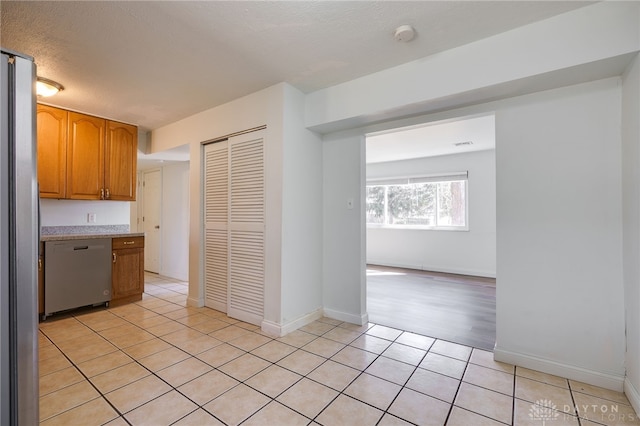 kitchen with stainless steel appliances, baseboards, light countertops, and light tile patterned flooring