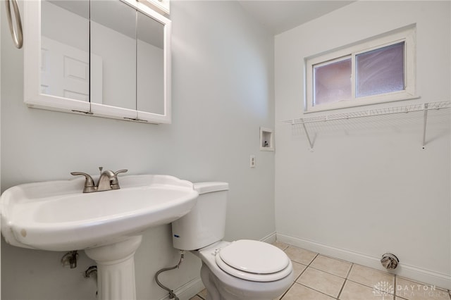 bathroom featuring baseboards, a sink, toilet, and tile patterned floors