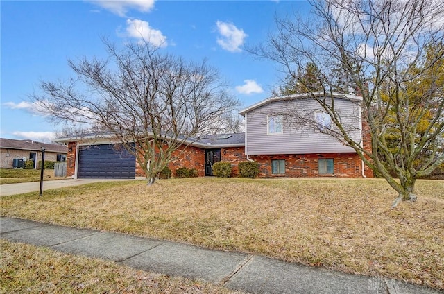 tri-level home with an attached garage, brick siding, concrete driveway, and a front yard