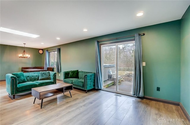 living area with light wood-style floors, plenty of natural light, and a notable chandelier