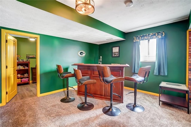 bar featuring a textured ceiling, a dry bar, carpet, and baseboards