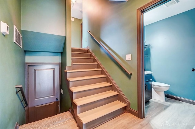 stairs featuring wood finished floors, visible vents, and baseboards