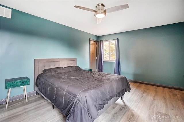 bedroom featuring light wood finished floors, baseboards, visible vents, and a ceiling fan