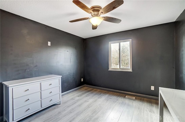 interior space with light wood-style floors, visible vents, ceiling fan, and baseboards