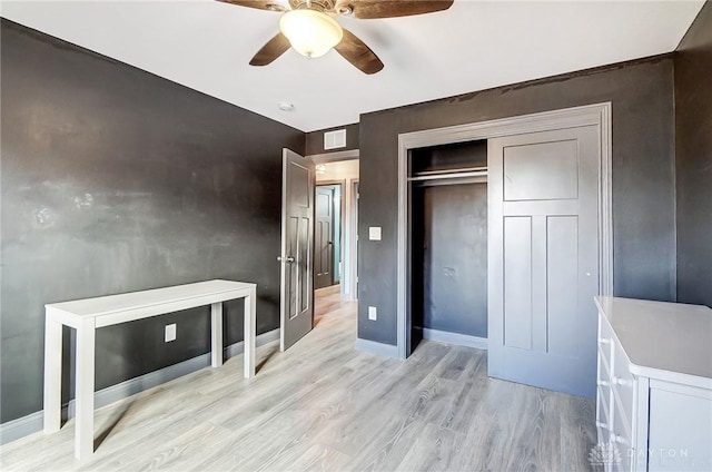 bedroom featuring light wood-style floors, ceiling fan, baseboards, and a closet