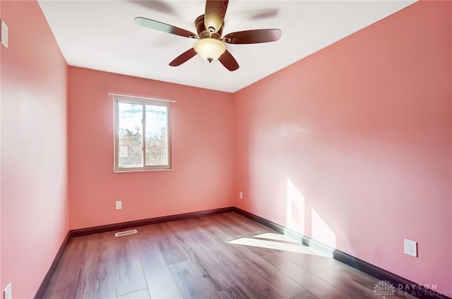 spare room with light wood finished floors, baseboards, visible vents, and a ceiling fan