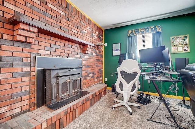 office area with brick wall, carpet flooring, a wood stove, and baseboards